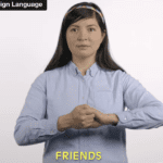 woman with long dark hair, light blouse, head band, with hands held together in front of her, caption in yellow on bottom center says FRIENDS, text at top left said INDIAN SIGN LANGUAGE white background